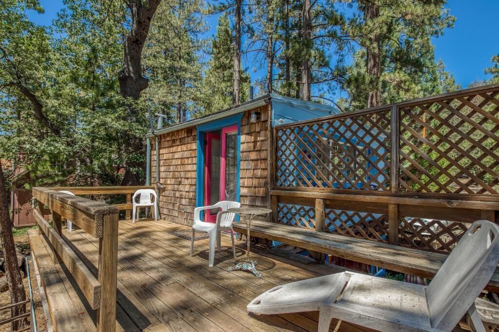A wooden deck with a small cabin, outdoor seating, and a lattice fence.