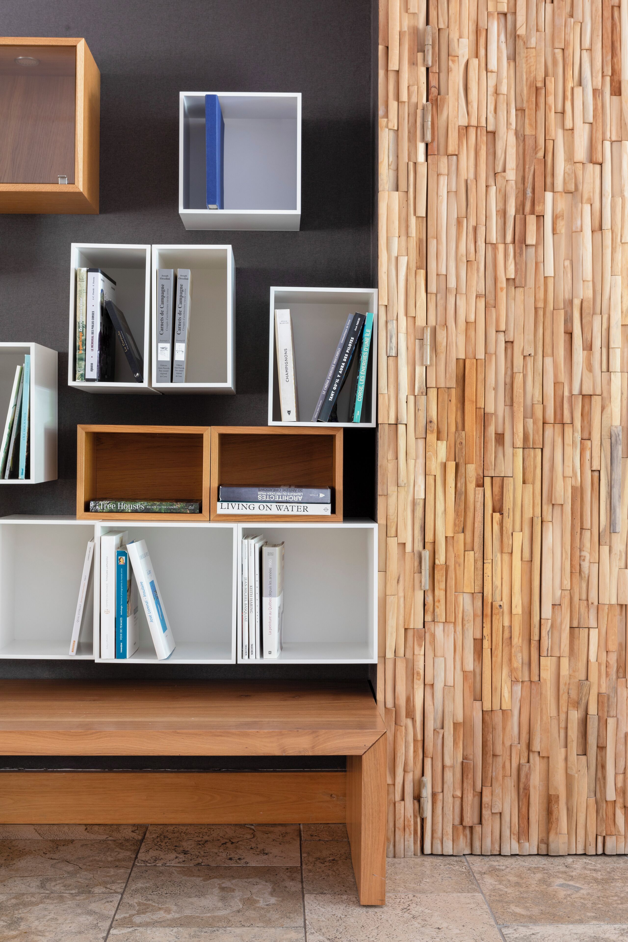 A modern bookshelf with books and a wooden bench.
