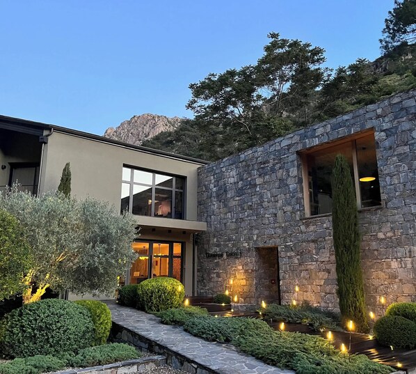 A modern building with a stone facade, large windows, and a well-lit entrance.