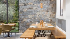 A dining area with a stone wall, wooden tables, and chairs.
