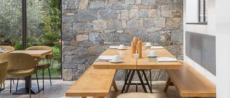 A dining area with a stone wall, wooden tables, and chairs.