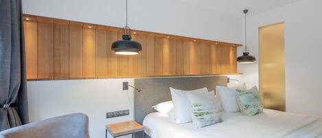 Una habitación de hotel moderna con una cama, una silla, una mesita y paneles de madera en la pared.