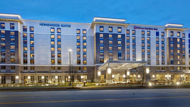Un hôtel à l’architecture moderne, dont la façade est ornée de deux enseignes bien visibles, l’une pour Homewood Suites et l’autre pour Hilton Garden Inn.