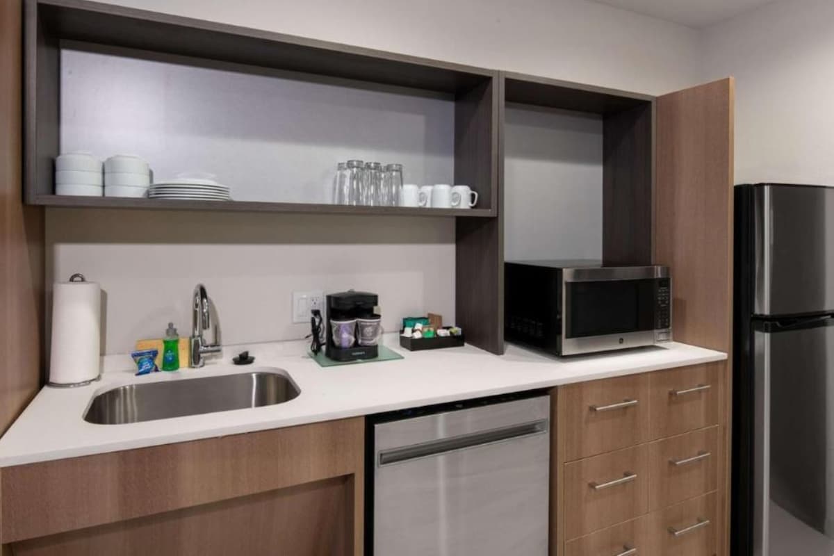 A modern kitchen with a stainless steel sink, a coffee maker, a microwave, and a refrigerator.