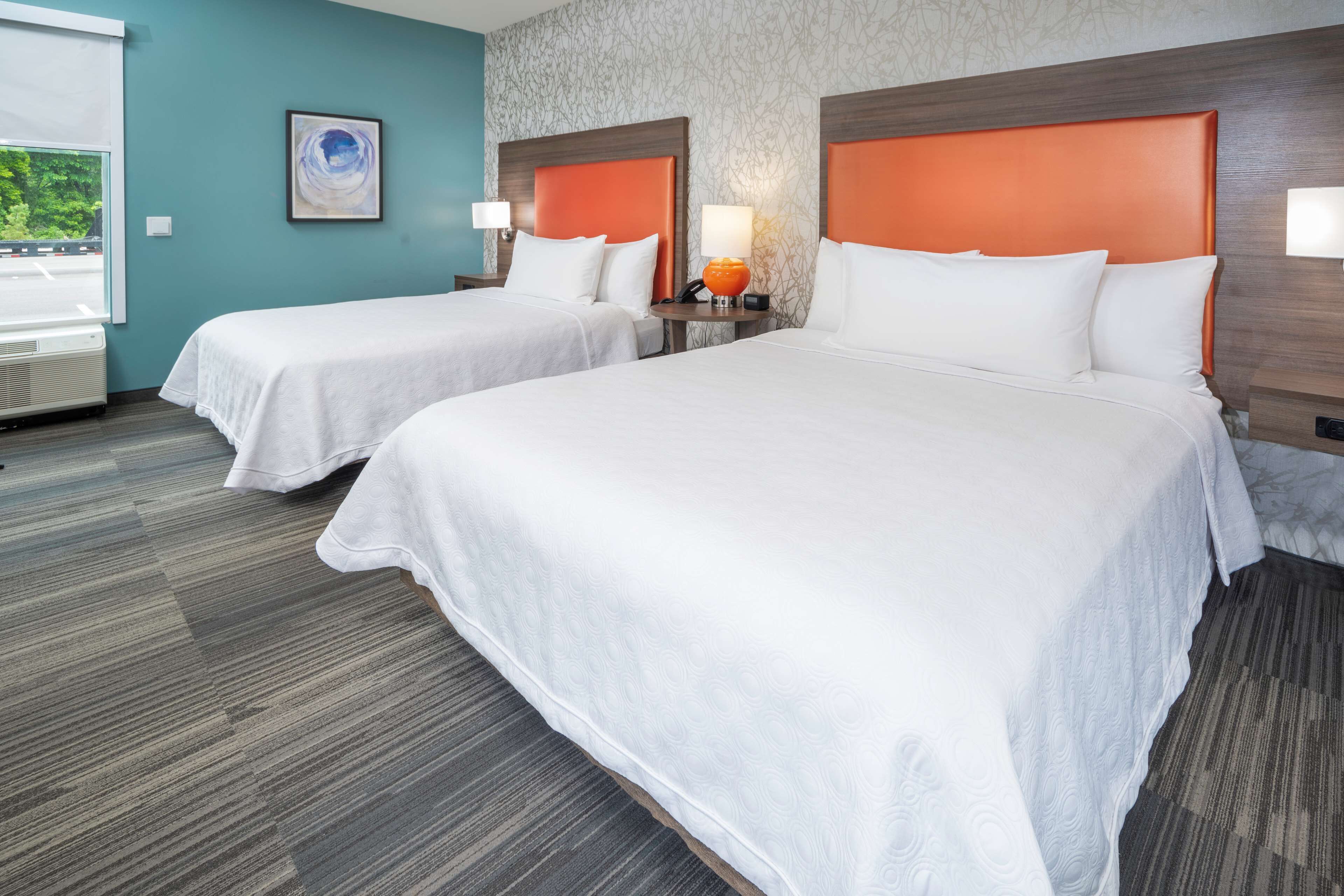 A hotel room with two beds, a window, and a wall with a textured pattern.