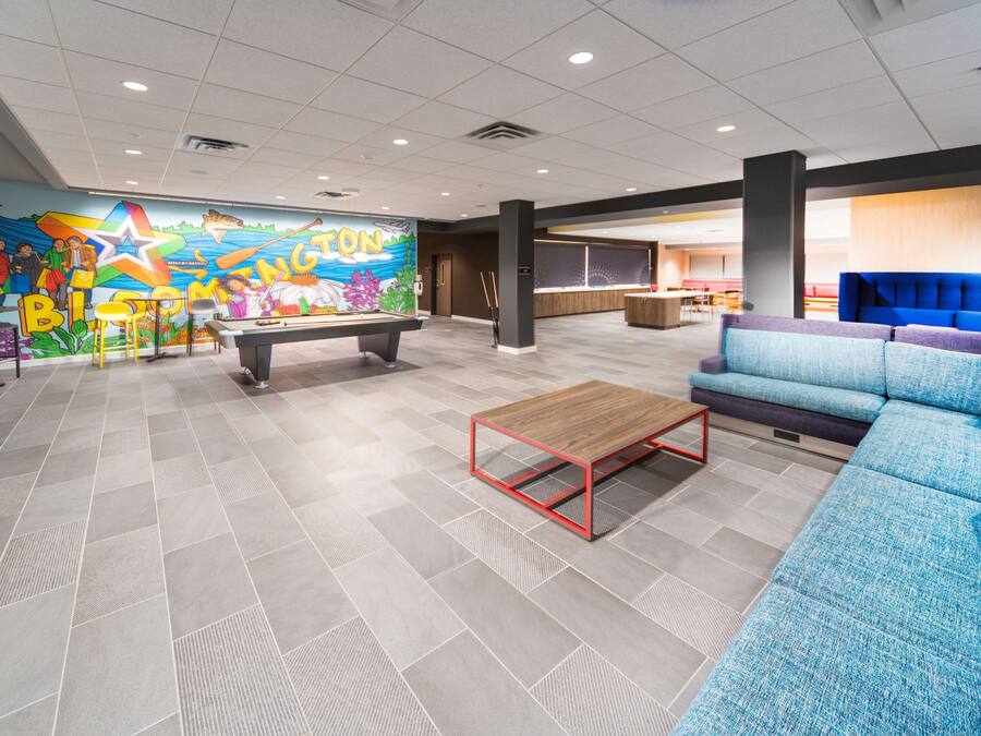 A lobby with a colorful mural, a pool table, a blue sofa, and a reception area.
