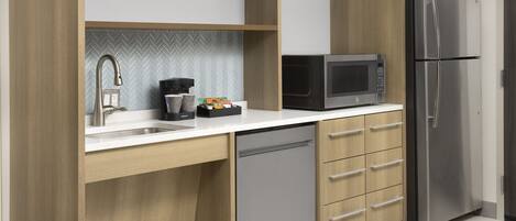Eine moderne Küche mit Geschirrspüler, Edelstahlkühlschrank, Mikrowelle und Holzschränken.