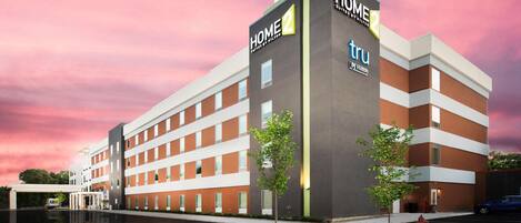 A modern hotel building with multiple floors, a prominent "HOME 2" sign, and a reflection pool in front.