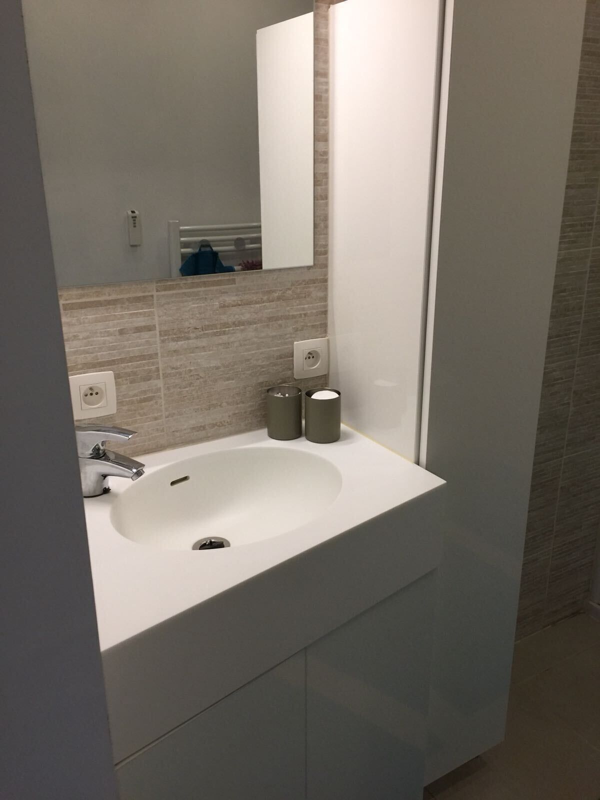 Een moderne badkamer met een witte wastafel, een spiegel en een handdoekhouder.