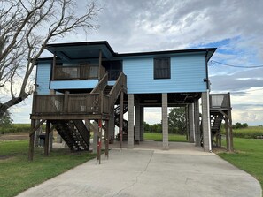 Una casa de dos pisos con un balcón de madera y escaleras que suben al nivel superior.