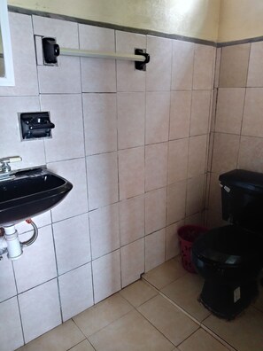 Un baño con lavamanos, inodoro y toallero.