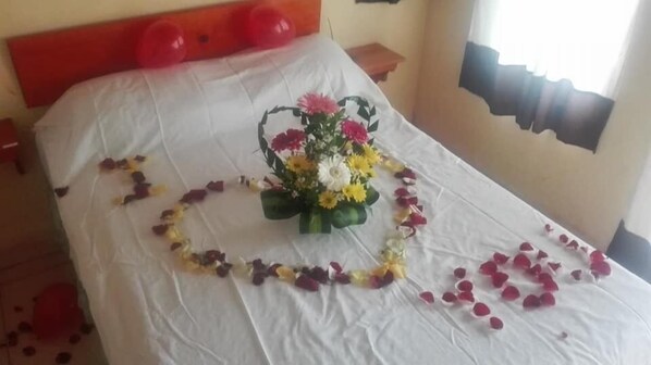 A bed with a heart-shaped arrangement of rose petals and a bouquet of flowers. - La Cabaña del Lago (Catemaco)