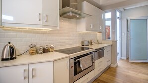 A modern kitchen with white cabinetry, a stainless steel kettle, and a built-in oven. - Sublime Cottage near Table Mountain and Kloof Street (Tamboerskloof)