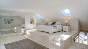 A spacious bedroom with a large bed, a glass partition, and a skylight. - Sublime Cottage near Table Mountain and Kloof Street (Tamboerskloof)