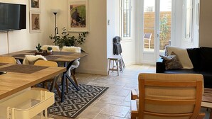 Un salon spacieux comprenant un coin repas, un canapé noir et un téléviseur fixé au mur.
