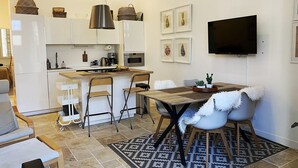 Une cuisine compacte avec un coin repas, un téléviseur fixé au mur et un tapis à motifs.