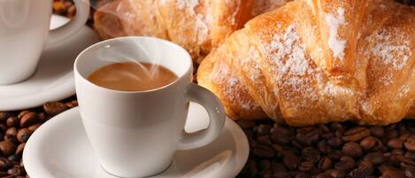 A cup of coffee with steam, a pastry, and coffee beans.