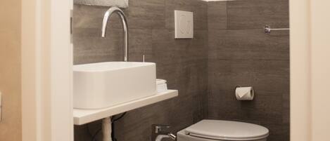 A modern bathroom with a sink, bidet, and toilet.