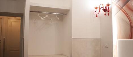 A bedroom with a bed, a bedside table, a wardrobe, and a wall-mounted light fixture.