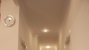 A narrow hallway with a clock on the left, a fire extinguisher in the middle, and doors on both sides leading to rooms. - Rubino Guest House (Rome)
