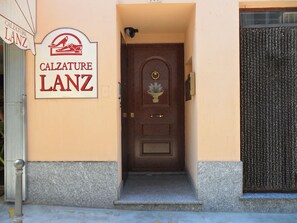 A building entrance with a sign reading "Calzature Lanz" and a wooden door with a decorative plate.