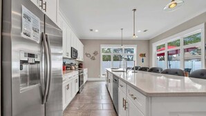 A modern kitchen with stainless steel appliances, white cabinetry, and a large island. - Iorana II | A Perfect Autumn Escape! | Game Room | Private Pool | Sleeps 21, Huge Private Master Suite! |  2 PM Check In!  |Gated Community with Amenities (Miramar Beach)