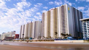 A high-rise hotel with multiple balconies, located near a beach with a sandy shoreline. - Good Times and Tan Lines! (Daytona Beach)