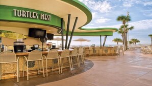 A beachside bar named "Turtles Nest" with outdoor seating and a view of the ocean. - Good Times and Tan Lines! (Daytona Beach)