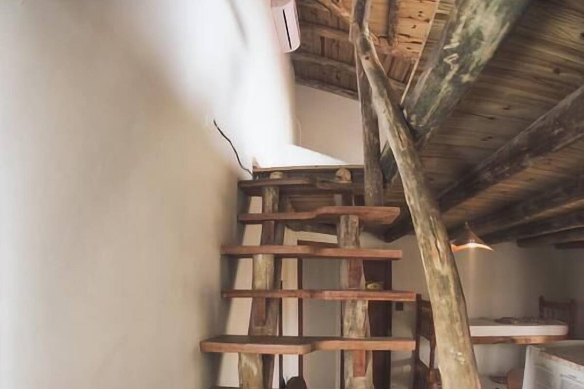 A spiral staircase with wooden steps and a rustic ceiling.