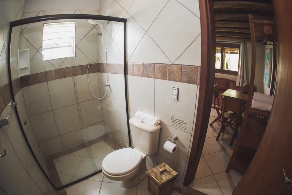 Casa de banho com chuveiro em cabine de vidro, sanita e lavatório.