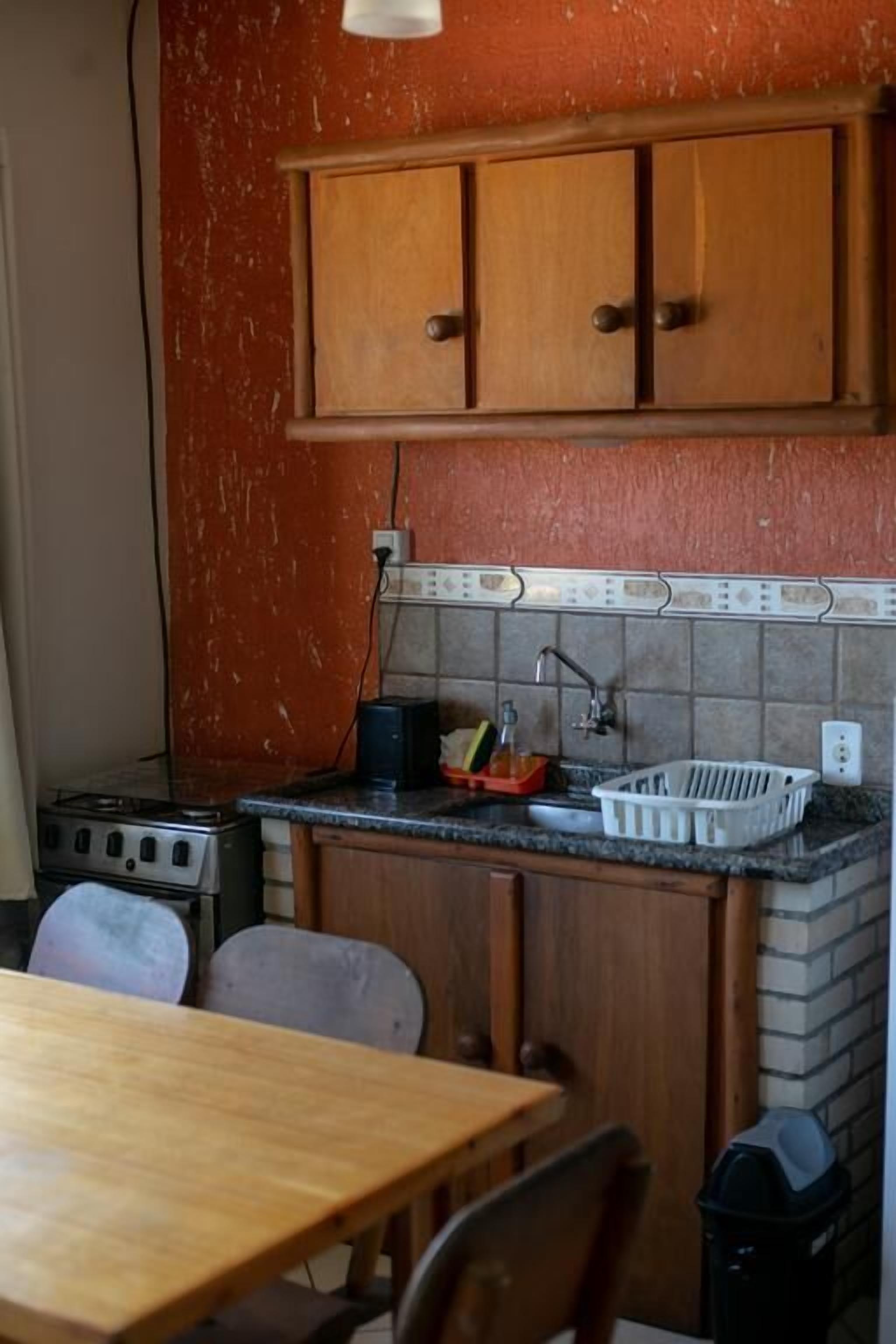 Una cocina compacta con armarios de madera, salpicadero de azulejos y encimera de granito.