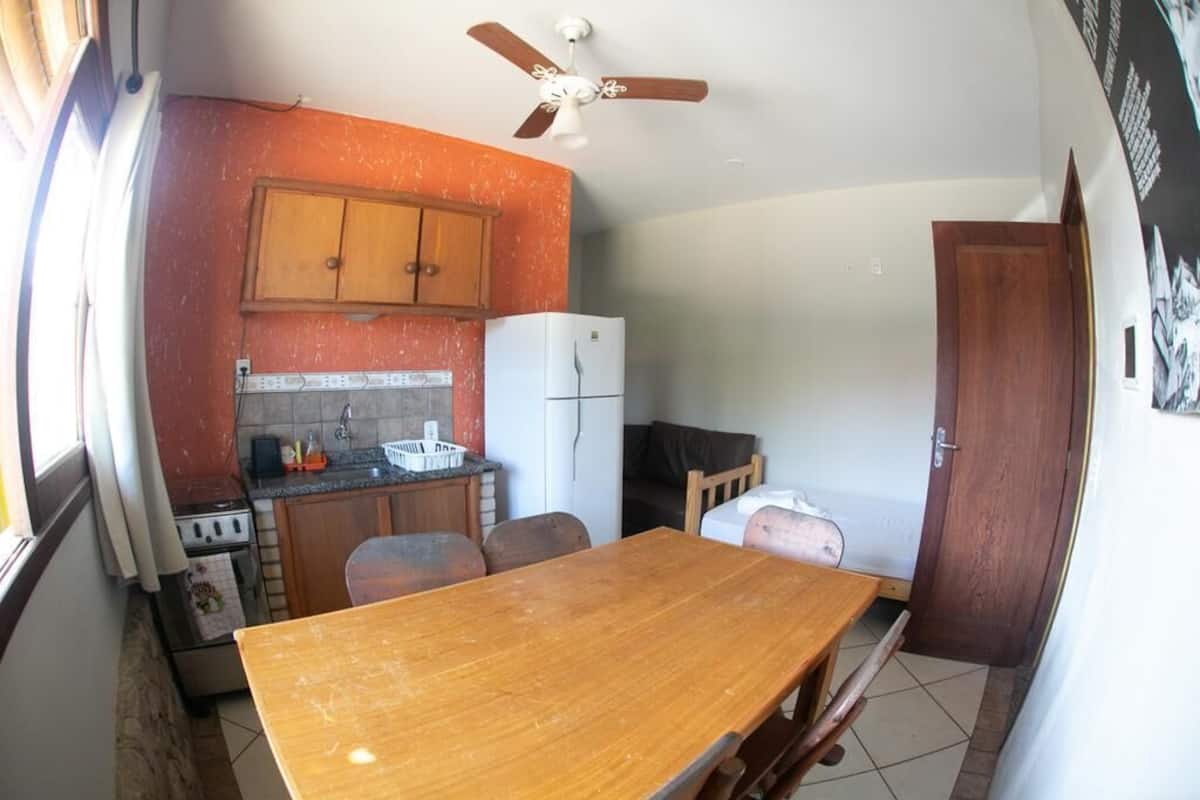 A compact kitchen with a wooden table, cabinets, a refrigerator, and a ceiling fan.