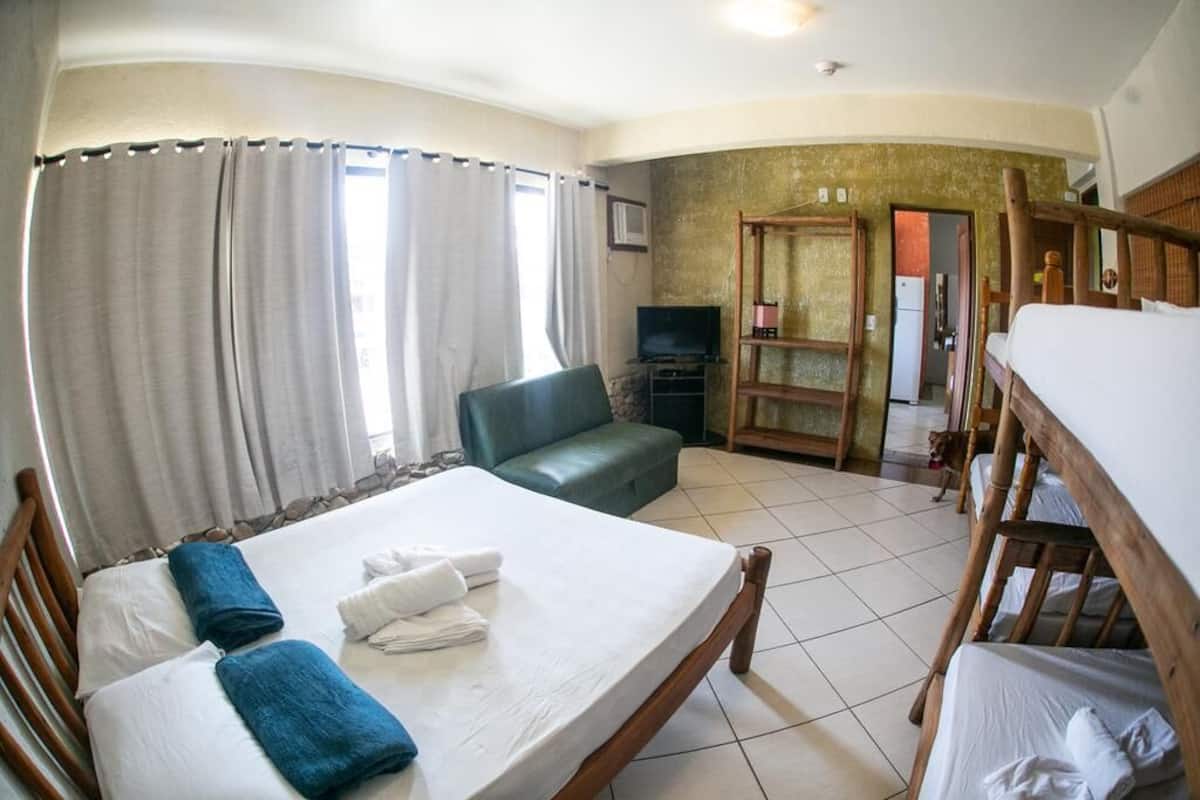 A room with a bed, a sofa, a television, and a dog.