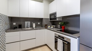 Una cocina moderna con armarios blancos, microondas, tostadora y pileta.