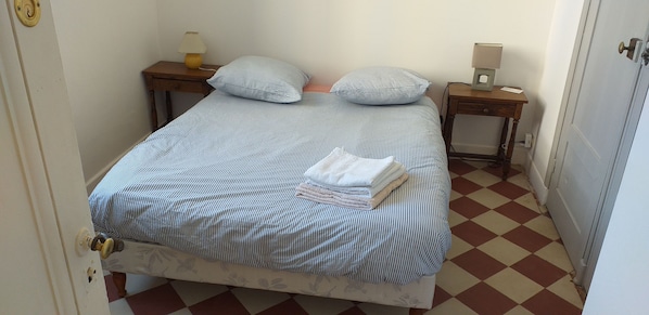 A bed with striped bedding, two bedside tables with lamps, and a checkered floor.