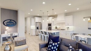 A modern kitchen with white cabinets, stainless steel appliances, and pendant lighting.