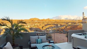 Ein Balkon mit Blick auf eine Wüstenlandschaft, eine Sitzecke mit Kissen und eine Whirlpool-Badewanne.