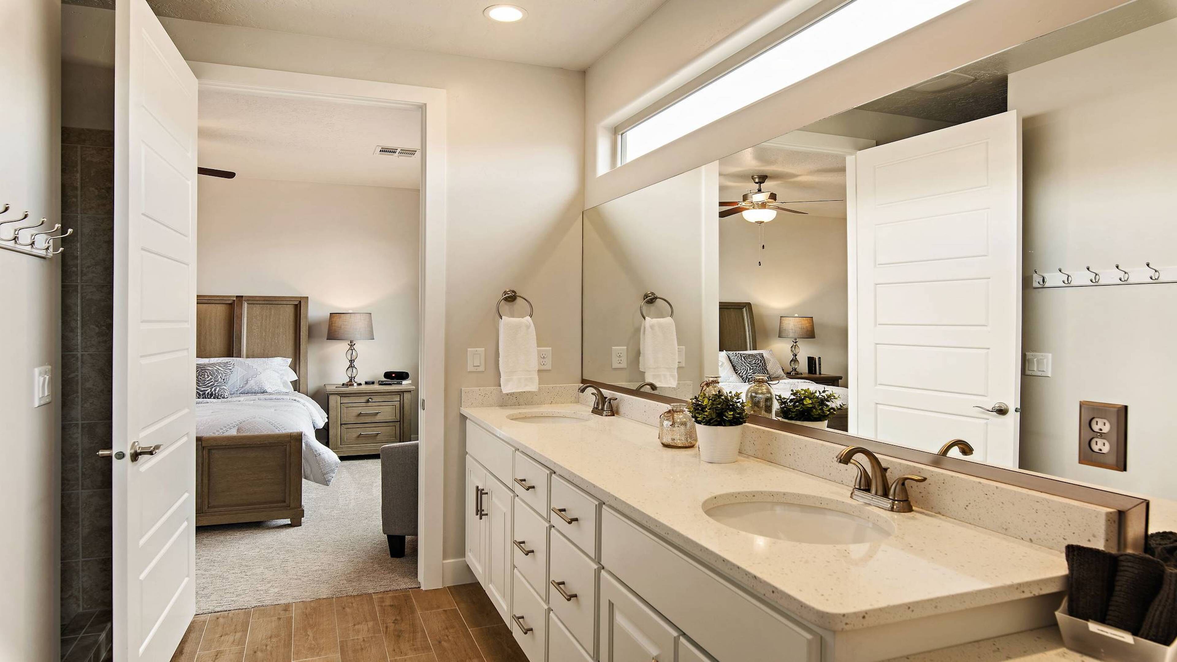 A modern bathroom with a large mirror, two sinks, and a walk-in shower.