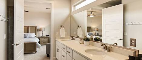 A modern bathroom with a large mirror, two sinks, and a walk-in shower.