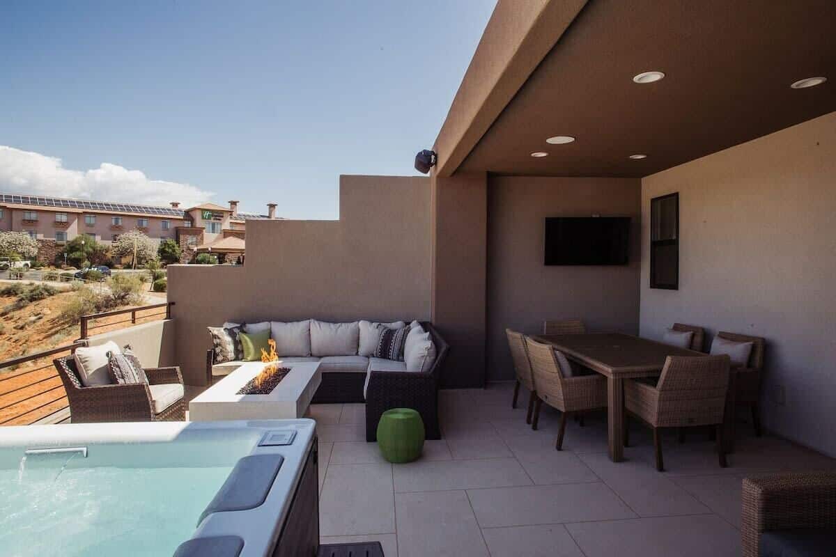 A rooftop patio with a hot tub, seating area, and a dining table.
