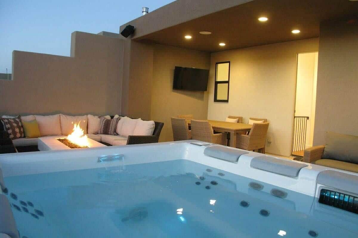 A hot tub area with a fire feature, seating, and a television.