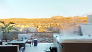 A hot tub on a balcony overlooking a desert landscape with houses in the background.