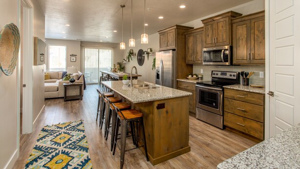 A spacious kitchen with wooden cabinets, stainless steel appliances, and a central island with bar stools.