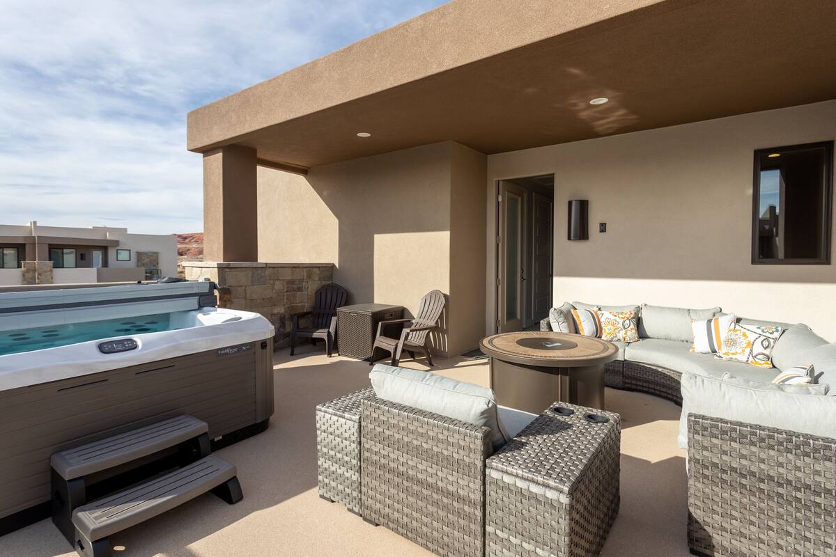 An outdoor patio with a hot tub, wicker furniture, and a stone wall.