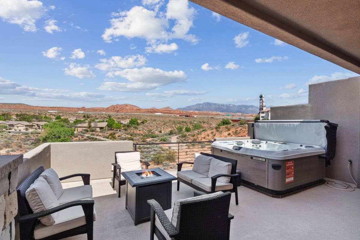 A balcony with outdoor furniture, a hot tub, and a scenic view of a desert landscape.