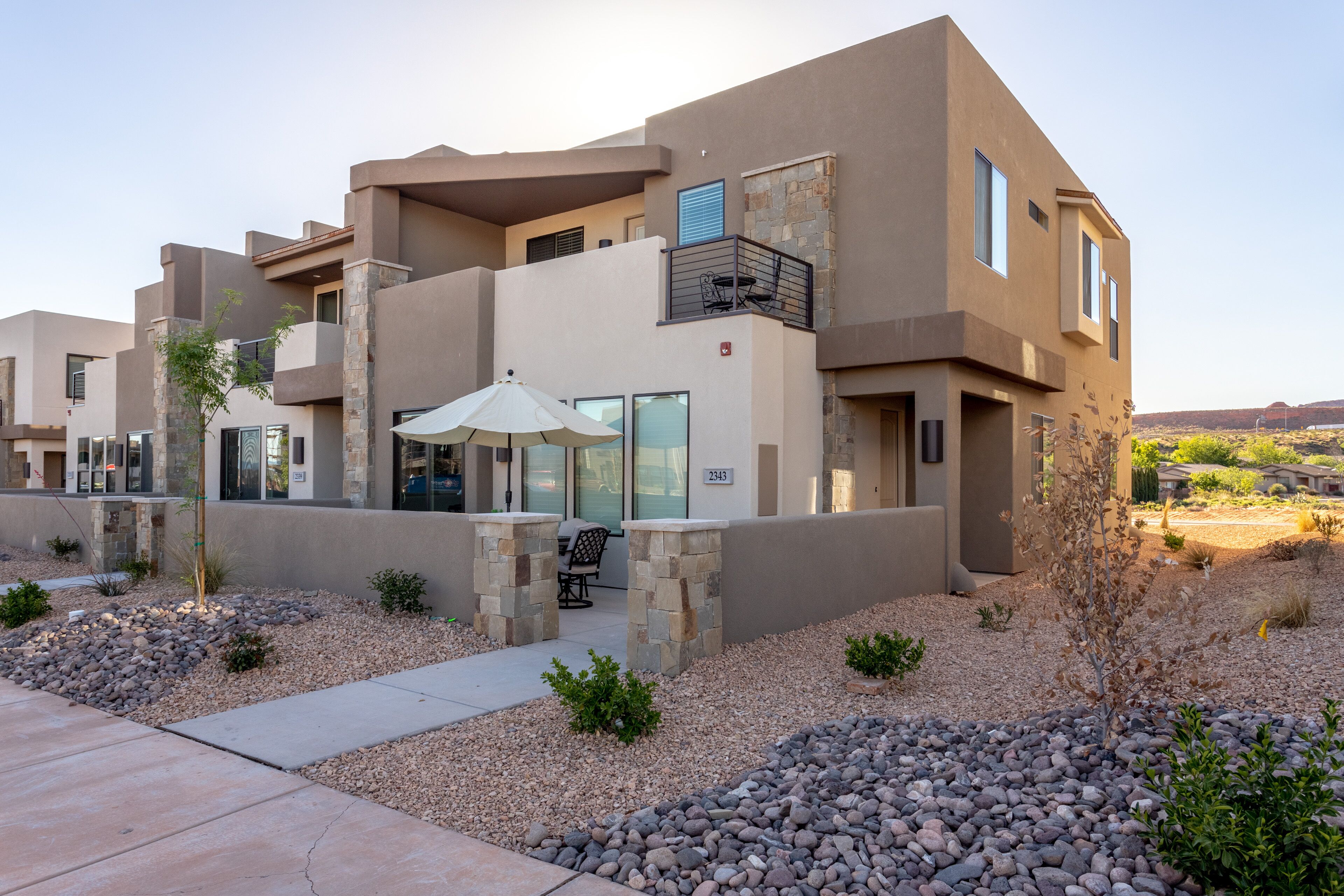 A modern multi-story building with a stone facade, outdoor seating, and a clear view of the surrounding landscape.