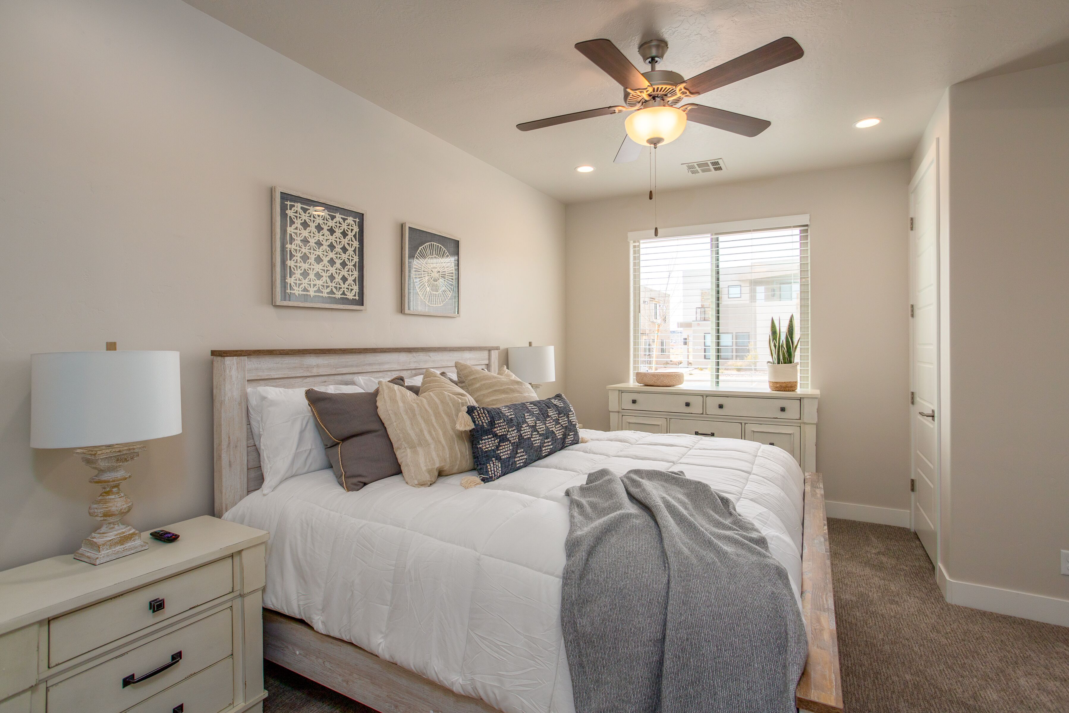 A bedroom with a bed, nightstands, a ceiling fan, and a window with blinds.
