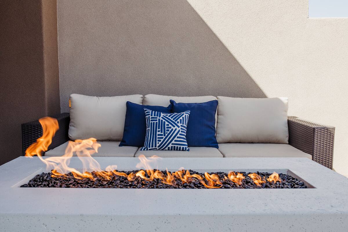 A fire pit with flames, a sofa with cushions, and a wall.