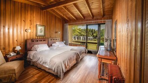 Een slaapkamer met houten lambrisering, twee bedden, een nachtkastje, een stoel en een houten bureau.