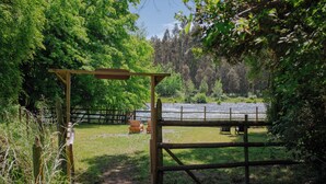 Een houten pergola leidt naar een gazon met uitzicht op een bebost landschap.